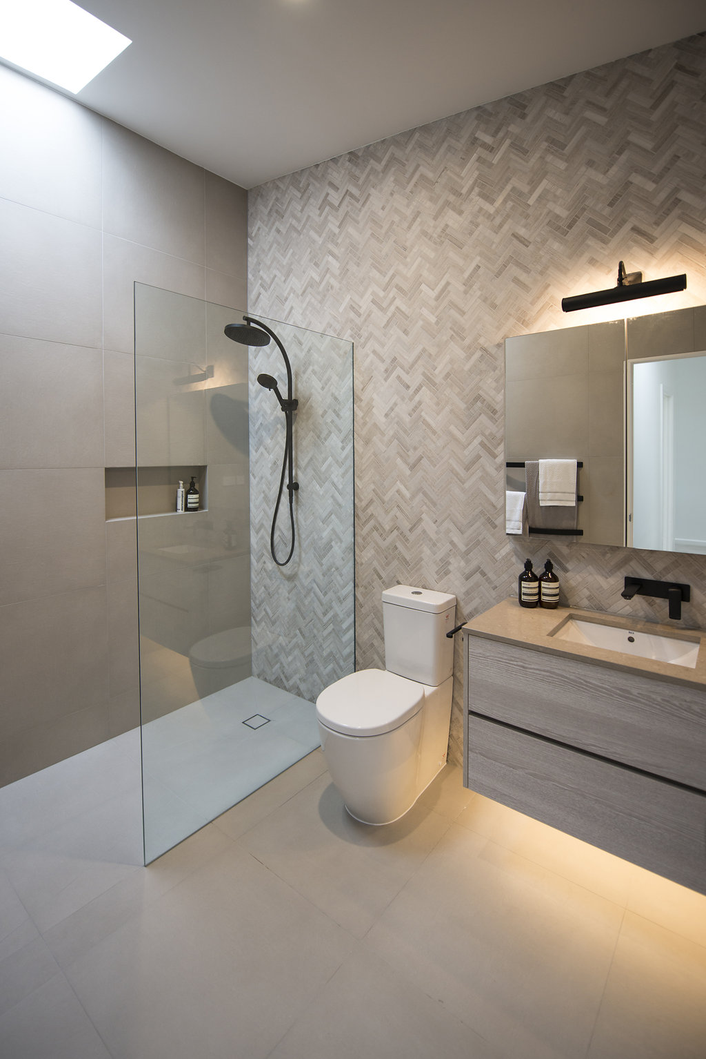 Herringbone tiles Southern tiles Feature wall Marble tiles Marble herringbone tiles Black tapware Shower niche Bathroom design Melbourne Bathroom design Carlton Bathroom design Marble tiles Herringbone marble tiles Modern vanity Medicine cabinet Shower niches Feature tiles Wall feature tiles